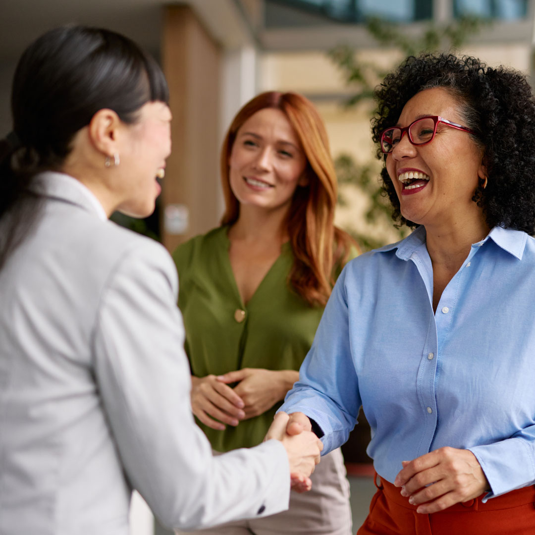 Two women smiling, shaking hands