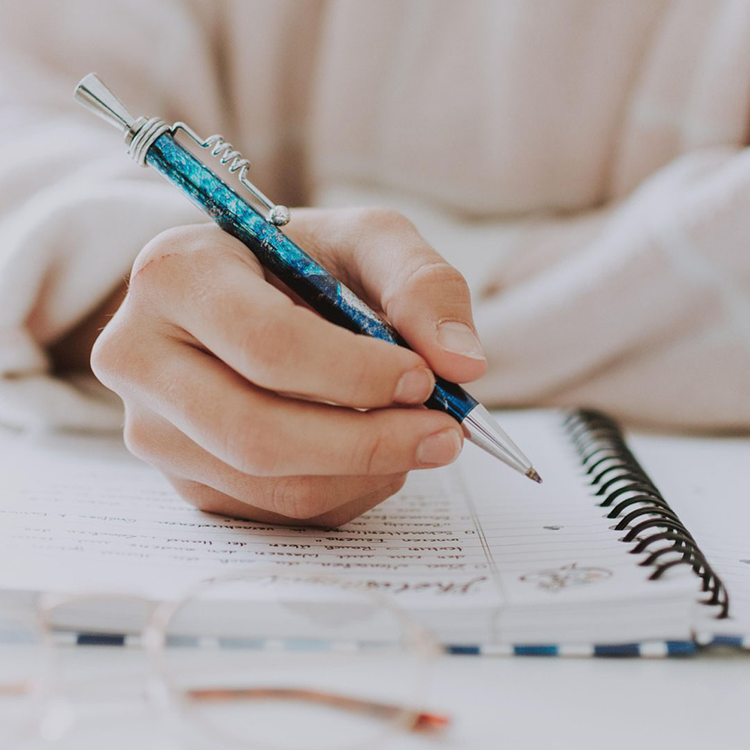 Hand holding pen writing in a notebook