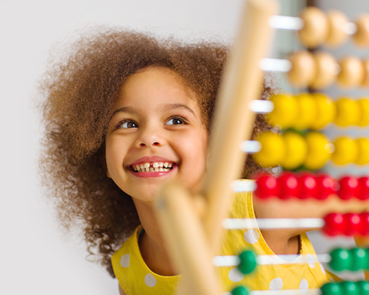 Young girl smiling with colored abacus in forefront of photo